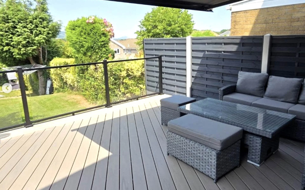 Composite deck with awning, glass balustrade and lounge seating in New Inn, Torfaen, near Cwmbran