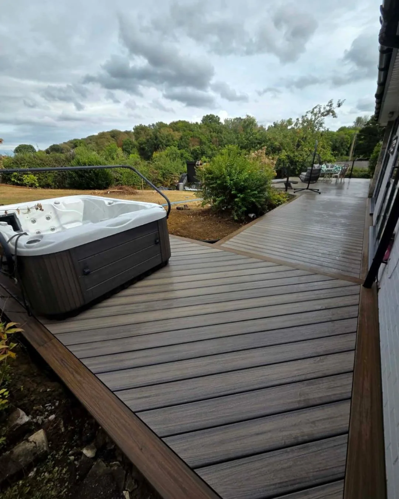 After: new composite deck wrapping around the house with the hot tub set into it