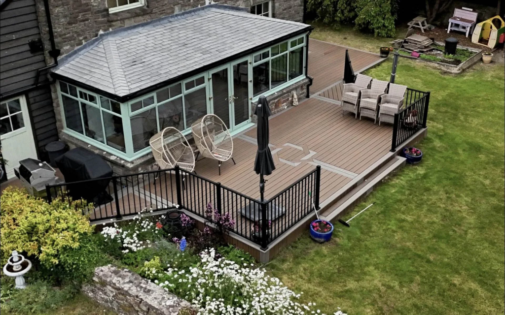 Trex composite deck with black railings wrapping a conservatory in Usk
