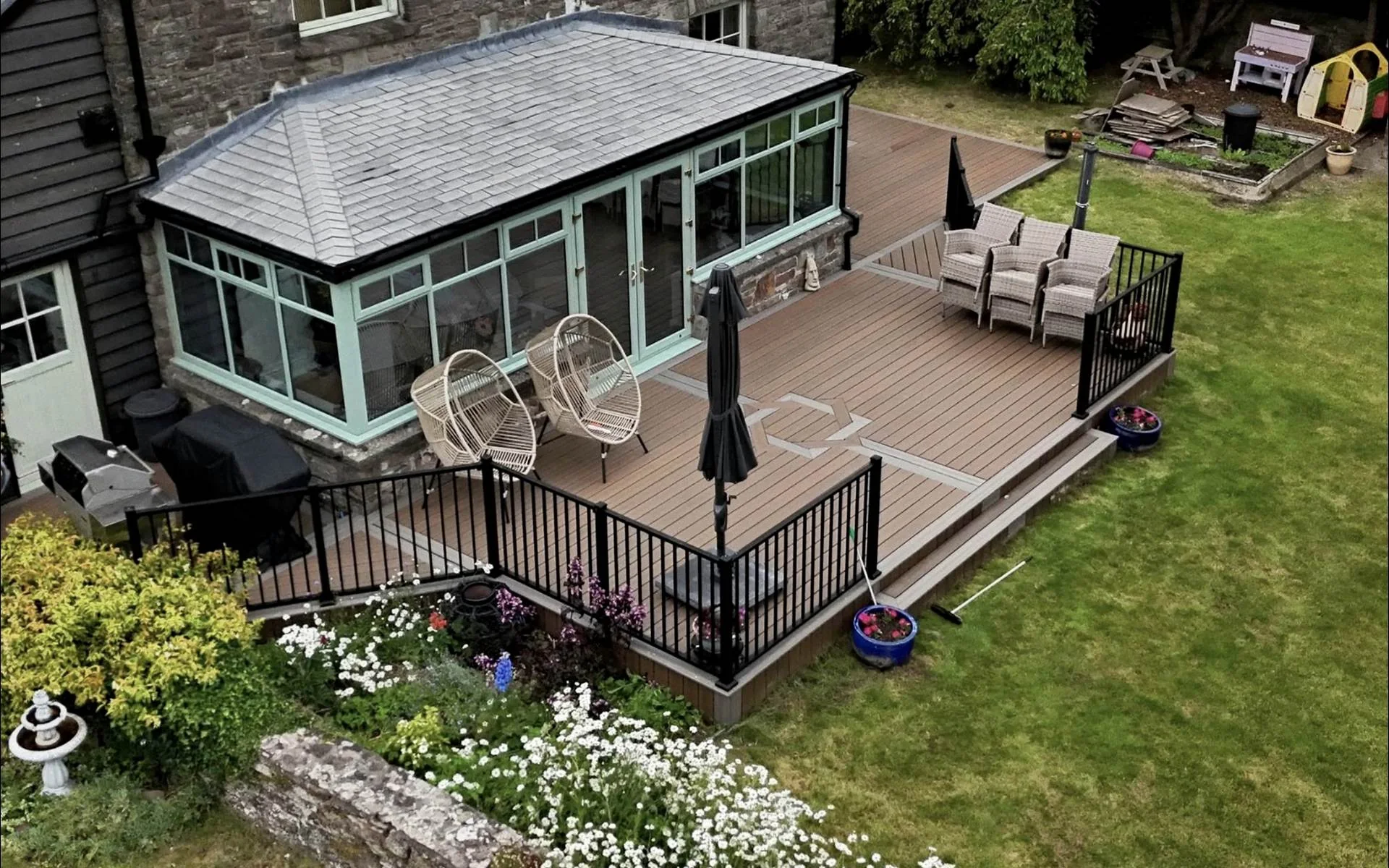 Trex composite deck with black railings wrapping a conservatory in Usk