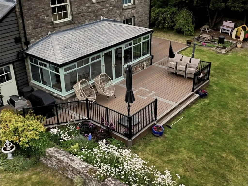 Finished Trex deck with black railings beside a conservatory