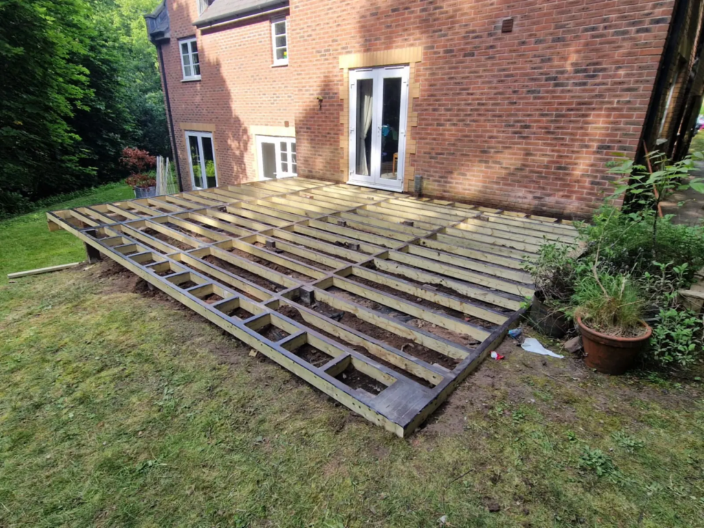 Composite deck subframe on the lawn behind a brick house