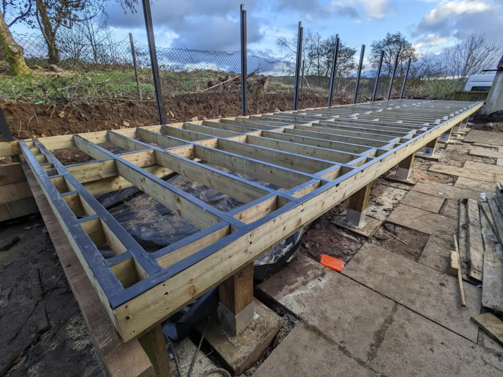 Composite deck subframe built on a slope with posts and footings