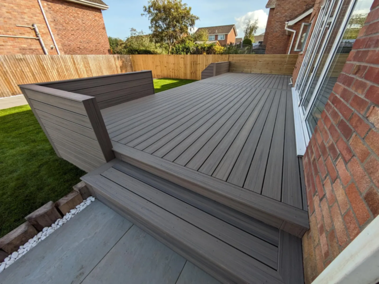 Dark composite deck with planter and wide steps down to the lawn