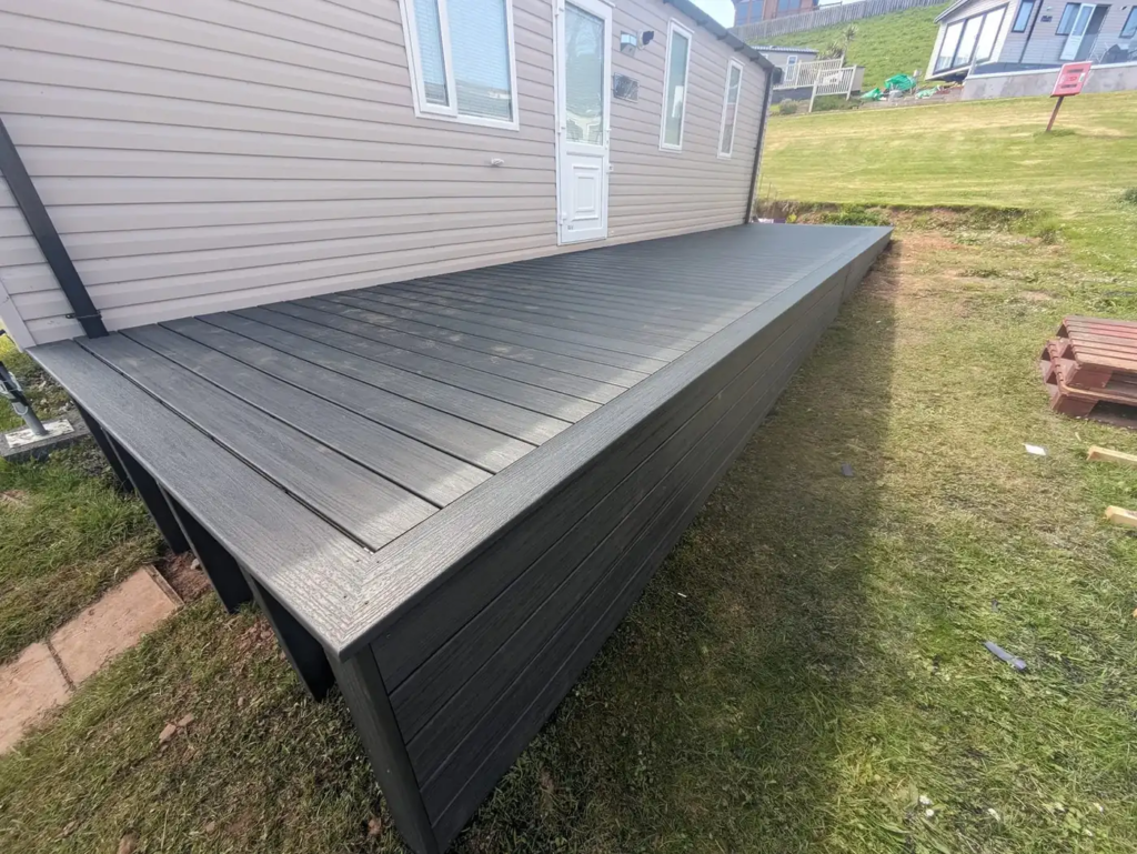 Dark grey Trex deck with matching skirting along a static caravan at a holiday park in Port Eynon