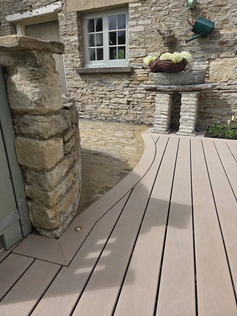 Curved Trex decking meeting Cotswold stone and a stone pillar