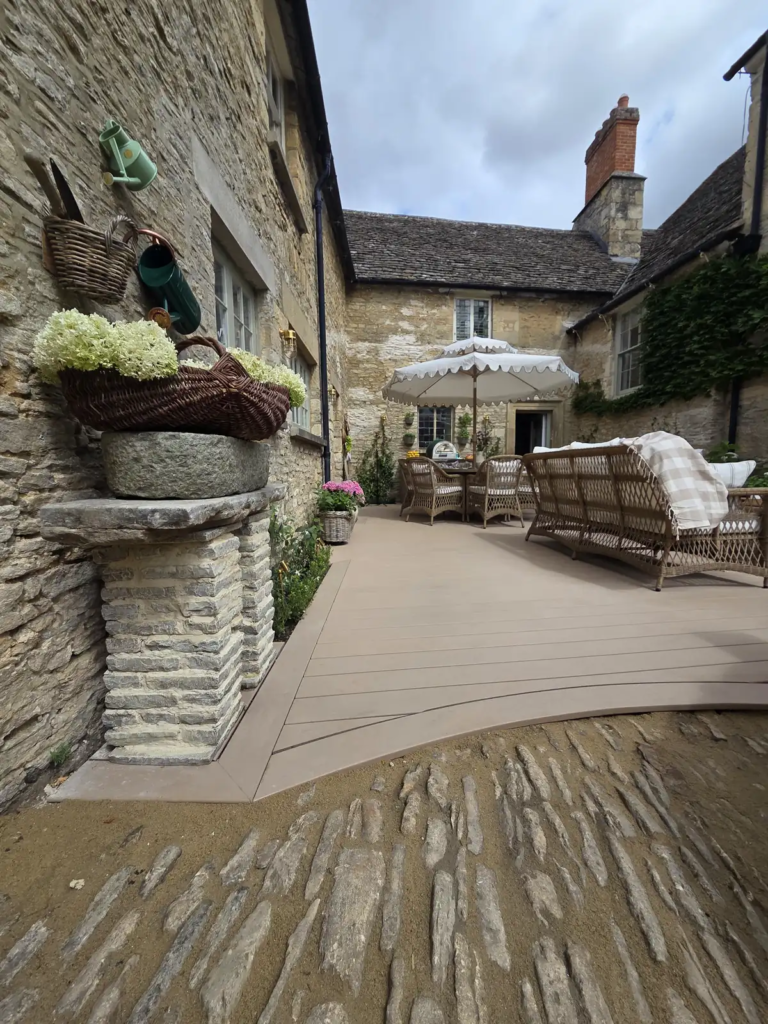 Curved Trex deck with planters beside Cotswold stone walls