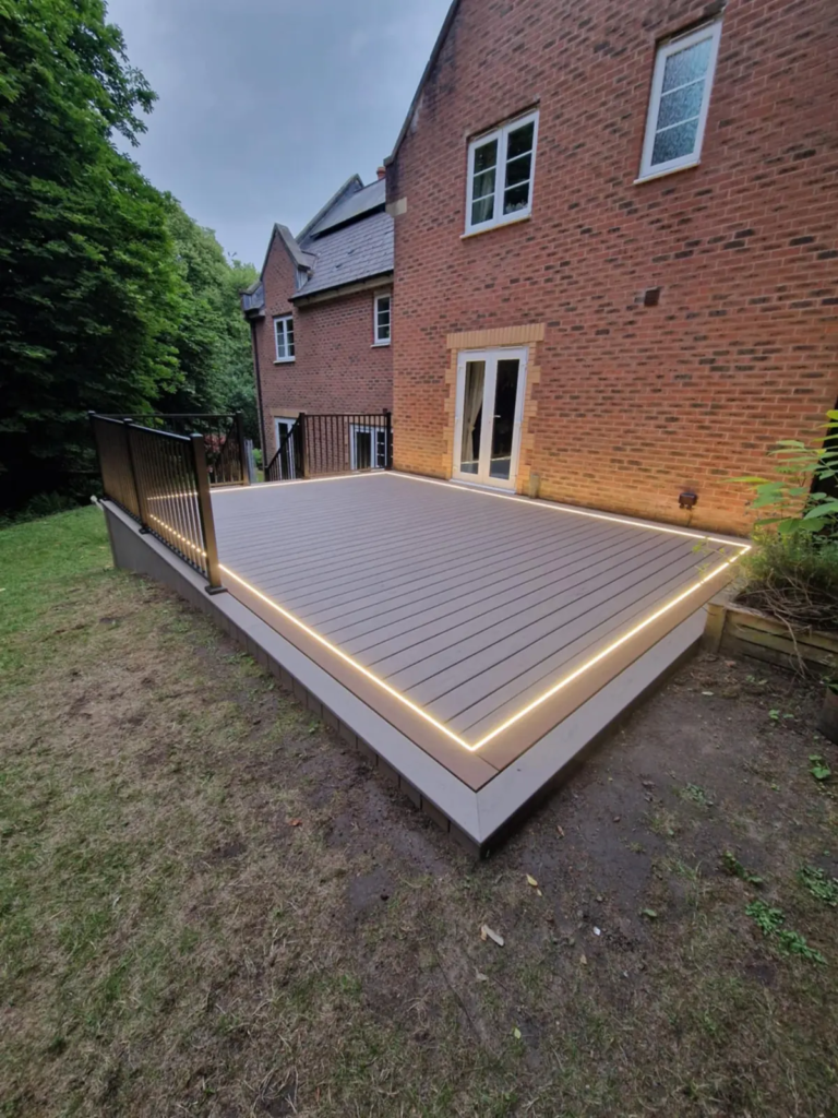 Finished Trex composite deck with LED edge lighting behind a brick house